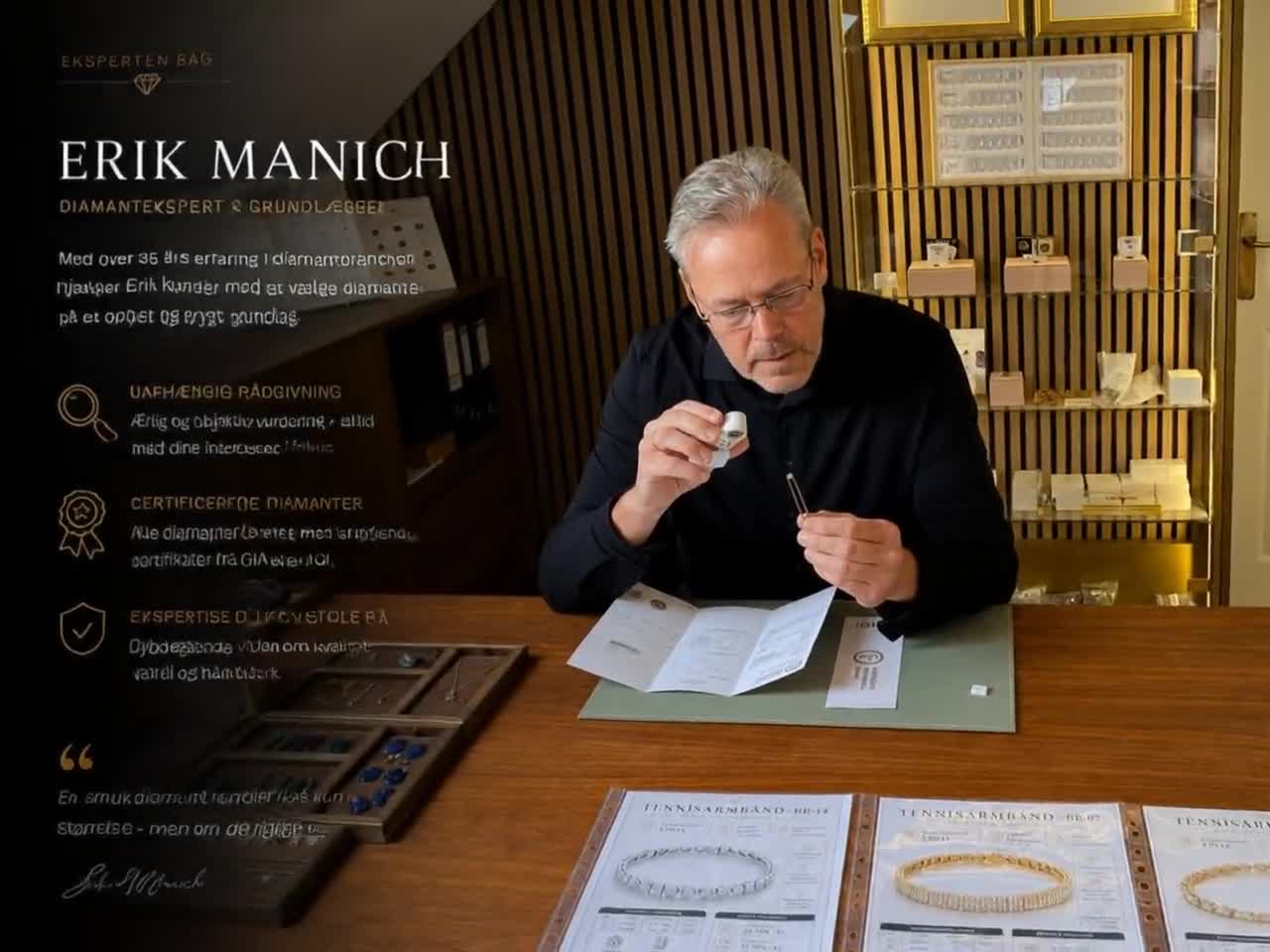 Erik Manich i sit showroom, fotograferet mens han vurderer en diamant gennem en juvelers loupe ved sit arbejdsbord. Bag ham GIA- og IGI-certifikater og diamanter i glasvitriner. På bordet ligger åbne certifikatrapporter og prisopslag for tennisarmbånd. Eksperten bag — Erik Manich, diamantekspert og grundlægger.