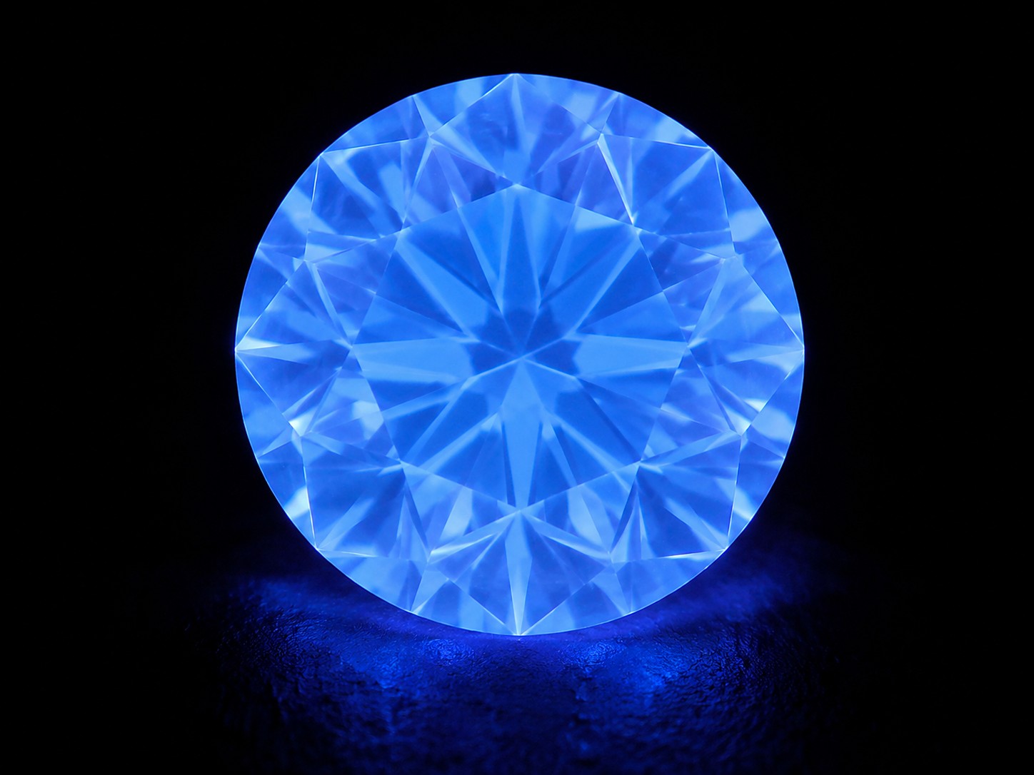 Samme diamant fotograferet under UV-lys, tydelig blå glød
